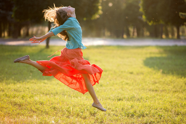 jonge vrouw springen in het park in beweging. Zachte achterkant licht - Foto, afbeelding