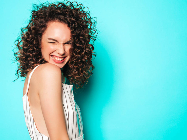 Portrait of beautiful smiling model with afro curls hairstyle dressed in summer hipster clothes.Sexy carefree girl posing near blue wall.Trendy funny and positive woman - Zdjęcie, obraz