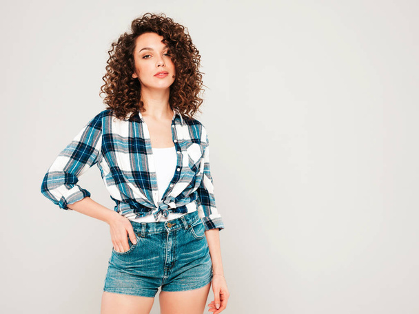 Portrait of beautiful smiling model with afro curls hairstyle dressed in summer hipster clothes.Sexy carefree girl posing in studio on gray background.Trendy funny and positive woman - Foto, afbeelding