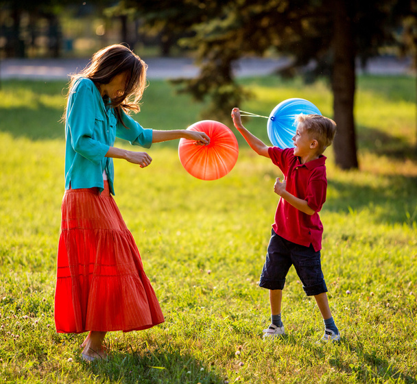 Mother and son having fun in the spring park in motion. backlit. focus on mother - Фото, зображення