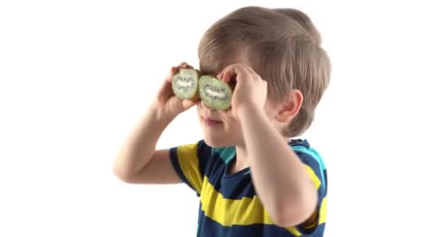 μικρό αγόρι ποζάρει στο στούντιο σε λευκό φόντο με κομμένο ακτινίδιο αντί για μάτια - Πλάνα, βίντεο