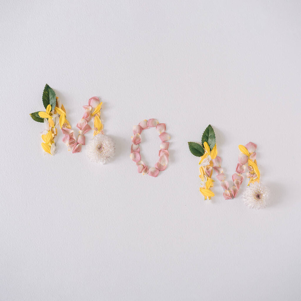 MOM word made with flower petals and leaves. Mother day natural creative concept background  - 写真・画像