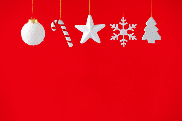 Decoración de Navidad colgando sobre fondo rojo. Concepto mínimo de vacaciones de invierno
. - Foto, Imagen