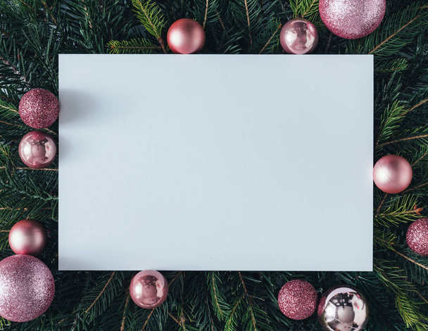 Természetes összetétel karácsonyfa ágakkal és rózsaszín baubles papír kártya jegyzet. Üdülési koncepció. - Fotó, kép