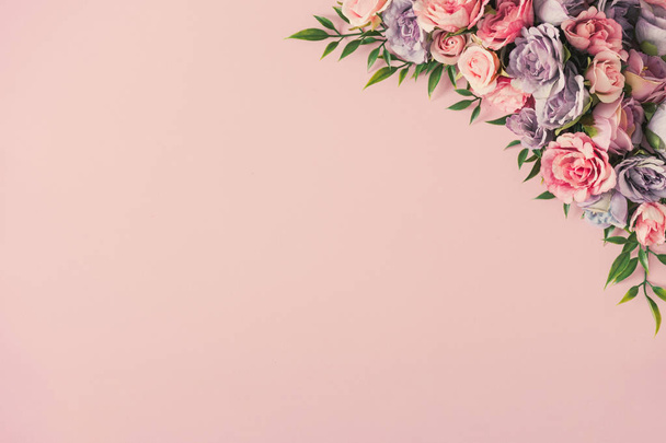 kreative Anordnung von bunten Blüten und grünen Blättern auf pastellrosa Hintergrund. Minimales Konzept zum Frauentag - Foto, Bild