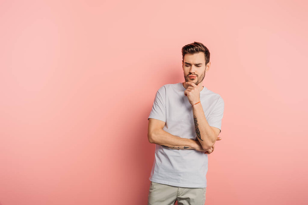 handsome thoughtful man touching chin on pink background - Фото, зображення