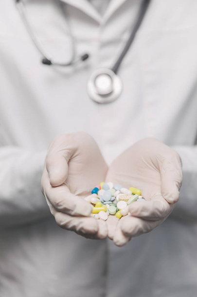 Zbliżenie męskiego lekarza dającego za dużo tabletek. Pojęcie przedawkowania - Zdjęcie, obraz