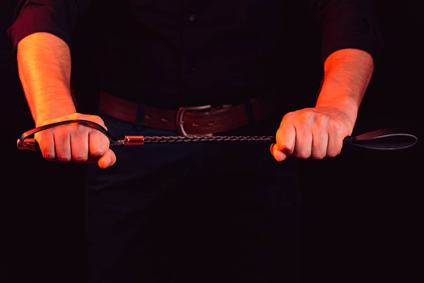Schöner Kerl mit einer BDSM-Peitsche in seinen Händen - Foto, Bild