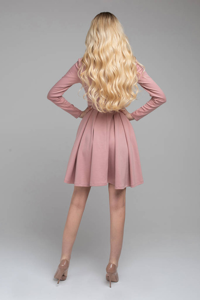 Λεπτή ξανθιά μοντέλο σε υπέροχο ροζ φόρεμα και μπεζ τακούνια. - Φωτογραφία, εικόνα