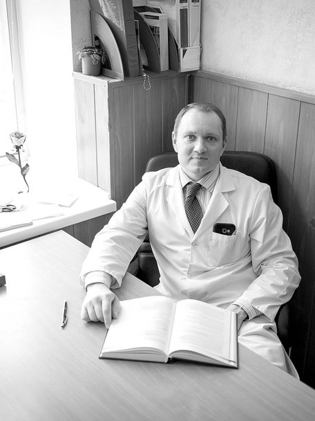 Doctor man sitting at the table at his workplace and smiling  - Photo, Image