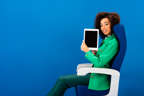 femme afro-américaine souriante tenant tablette numérique isolé sur bleu
  - Photo, image