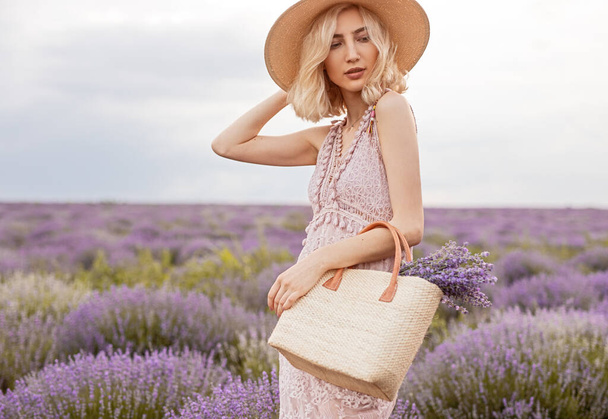 Stylish woman with bag in lavender field - Фото, зображення