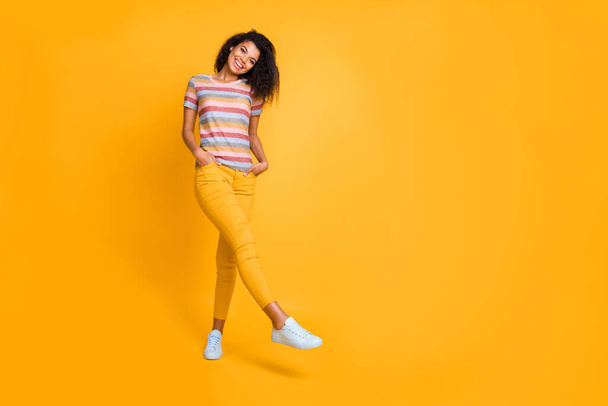 Full length body size view of nice attractive feminine charming cute cheerful cheery wavy-haired girl in striped t-shirt walking posing isolated on bright vivid shine vibrant yellow color background - Photo, Image
