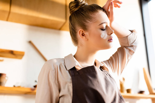 young tired woman with flour on face touching forehead  - Photo, Image