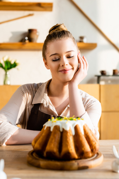 selective focus of happy woman looking at tasty easter cake  - Foto, imagen