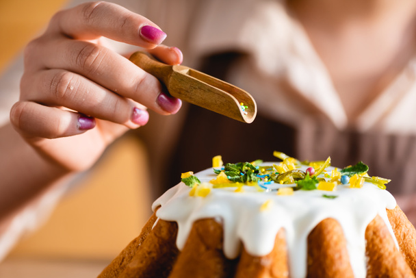 cropped view of woman holding wooden spoon with sprinkles near tasty easter cake  - Φωτογραφία, εικόνα