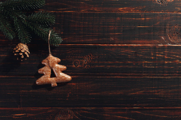 Biscoitos de gengibre de Natal e ramos de pinho e cones em um fundo de madeira, espaço de cópia
. - Foto, Imagem