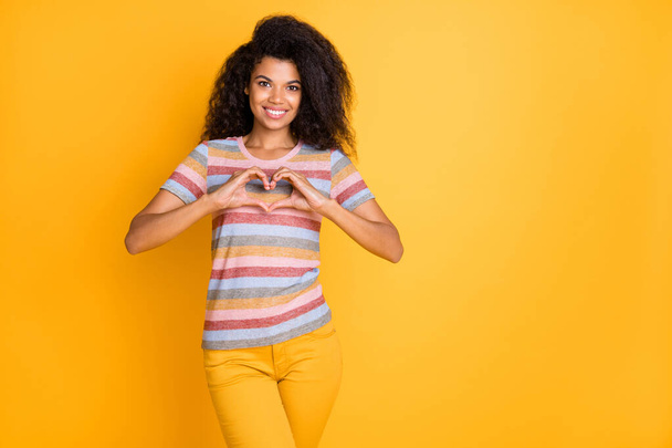 Portrait of nice attractive cheerful cheery kind sweet wavy-haired girl in striped t-shirt showing heart sign symbol isolated on bright vivid shine vibrant yellow color background - Fotografie, Obrázek