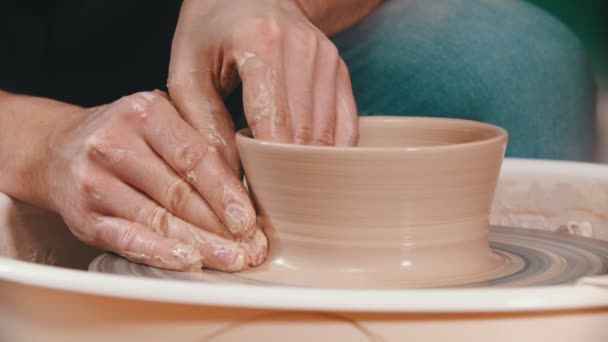 Pottery - mistr zvedá stěny hliněné misky s rukama na hrnčířském kole v kreativní dílně - Záběry, video