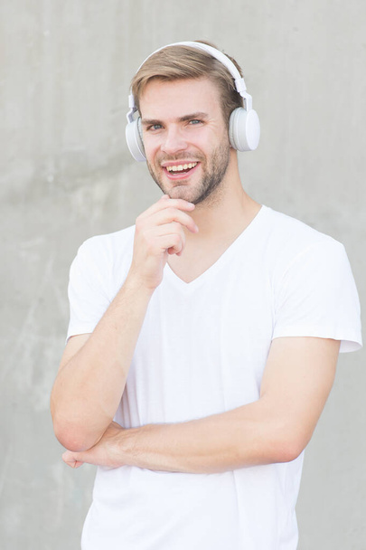Wireless Earpiece. Handsome guy wear headphones grey background. Man student listen modern music. Modern technology. Foldable Stereo Headphones. Noise Reduction. Modern and contemporary music - Photo, Image