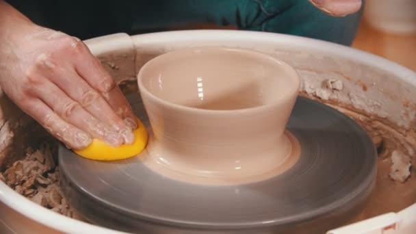Κεραμικά - ο κύριος σκουπίζει τον τροχό αγγειοπλαστών με ένα κίτρινο σφουγγάρι - Πλάνα, βίντεο