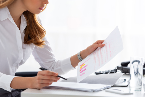 Cropped view of businesswoman working with documents and charts at table - Foto, Imagen