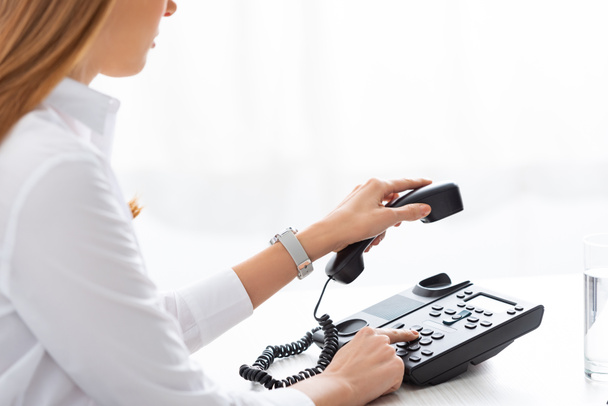 Обрізаний вид бізнес-леді тримає телефон під час використання телефону за столом
 - Фото, зображення