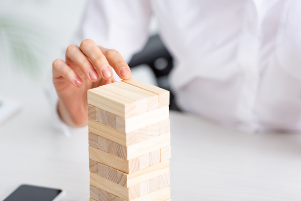 Enfoque selectivo de la mujer de negocios jugando bloques torre de madera juego en la mesa
  - Foto, Imagen
