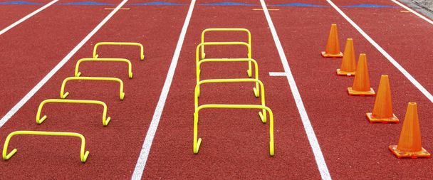 Mini hurdles and cones set up in lanes on a track for speed and  - Photo, Image