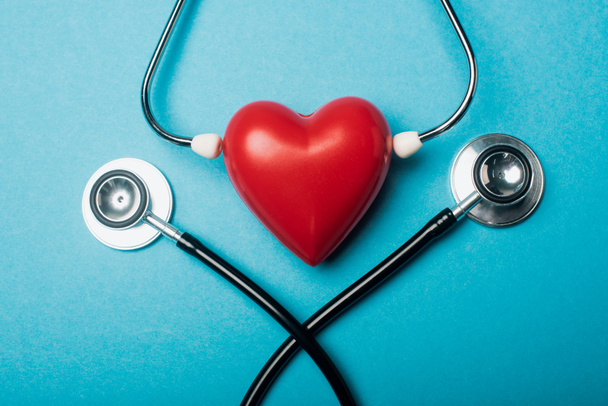 Top view of decorative heart with stethoscopes on blue background, world health day concept - Zdjęcie, obraz
