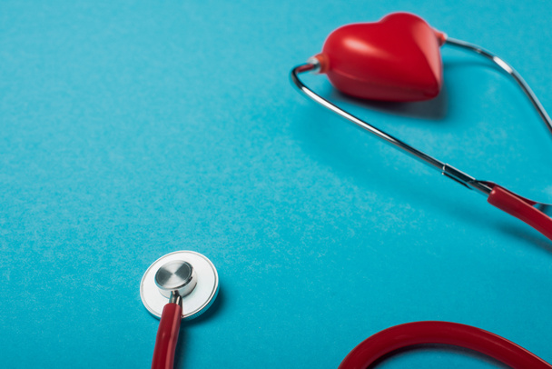 Stethoscope connected with decorative red heart on blue background, world health day concept - Foto, Imagem