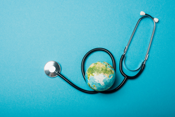 Top view of globe and stethoscope on blue background, world health day concept - Photo, Image