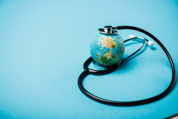 Stethoscope with globe on blue background, world health day concept - 写真・画像