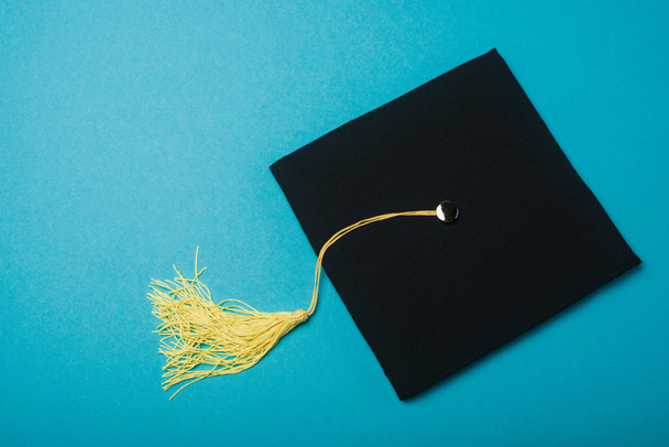 Black graduation cap with tassel brush on blue background - Zdjęcie, obraz