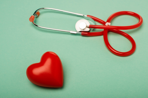 Stethoscope with decorative red heart on green background, world health day concept - 写真・画像