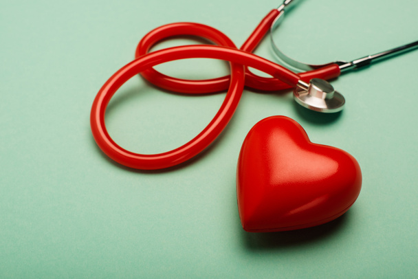 Stethoskop und rotes Herz auf grünem Hintergrund, Konzept zum Weltgesundheitstag - Foto, Bild