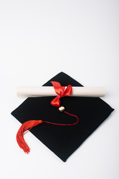 Diploma with nice bow on black graduation cap on white background - Photo, Image