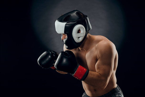 Portrait d'un jeune homme avec un casque de boxe et des gants sur un dar
 - Photo, image