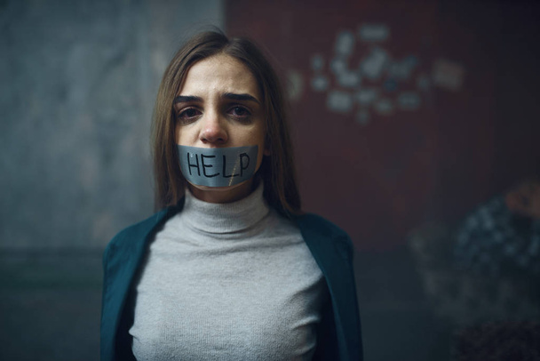 Female victim of maniac kidnapper with her mouth taped shut. Kidnapping is a serious crime, kidnap horror, violence - Fotoğraf, Görsel