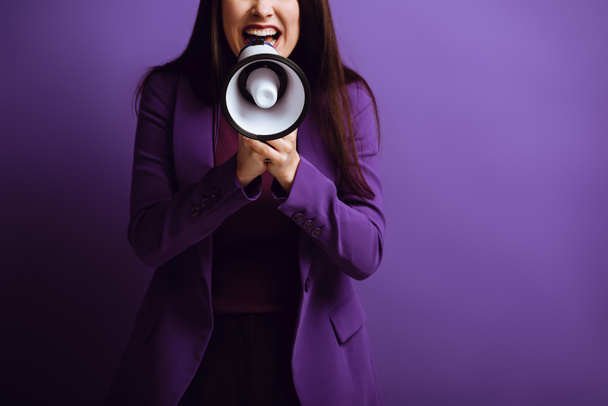 przycięty widok podekscytowanej kobiety krzyczy w megafonie na fioletowym tle - Zdjęcie, obraz