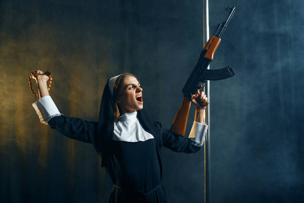 junge Nonne in Soutane hält Sturmgewehr in der Hand, bösartige Wünsche. korrupte Schwester im Kloster, Religion und Glaube, sündige religiöse Menschen, attraktive Sünderin - Foto, Bild