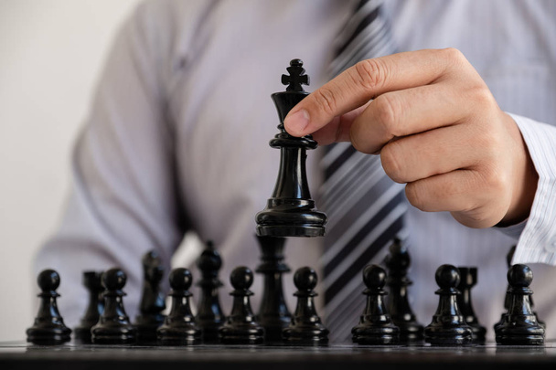 hand of businessman moving chess in competition, shows leadership, followers and business success strategies - Foto, imagen