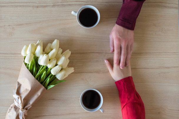 Valentines day.  Close-up of woman and man celebrating in restaurant. Boyfriend giving bouquet of tulips to girlfriend. love, romance, date. Flat lay - Foto, Imagen