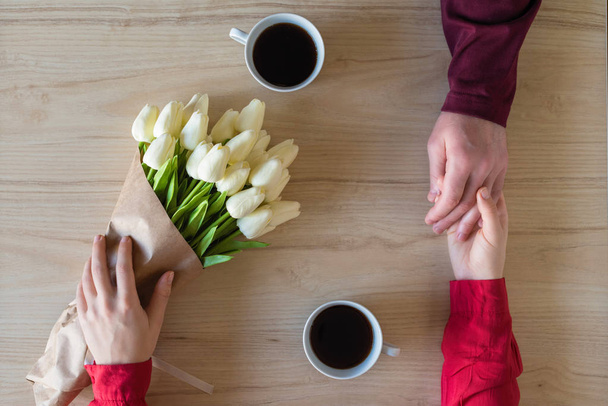 Valentines day.  Close-up of woman and man celebrating in restaurant. Boyfriend giving bouquet of tulips to girlfriend. love, romance, date. Flat lay - Foto, Imagen