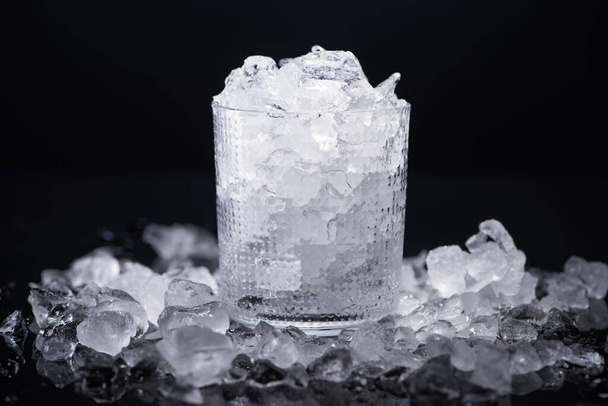 прозрачное стекло, наполненное разбитым льдом, изолированным на черном
 - Фото, изображение