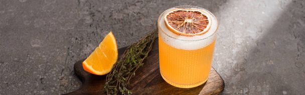cocktail with orange and herb on wooden cutting board on concrete surface, panoramic shot - Фото, зображення