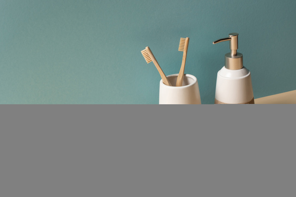 Toothbrushes, hair brush, liquid soap dispenser and sponge on beige and grey, zero waste concept - Фото, изображение