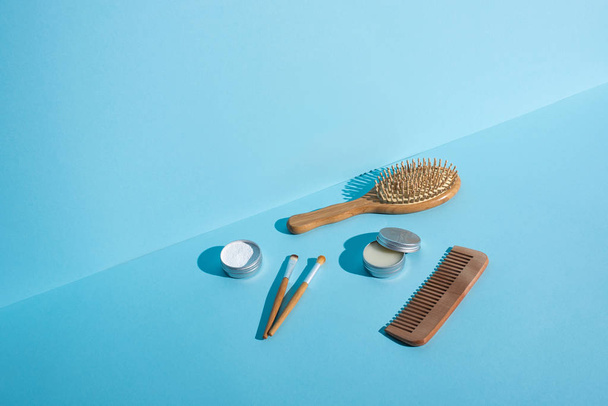 Hajkefe, fésű, viaszból és fogporból készült edények, kék hátterű kozmetikai kefék, zéró hulladék koncepció - Fotó, kép
