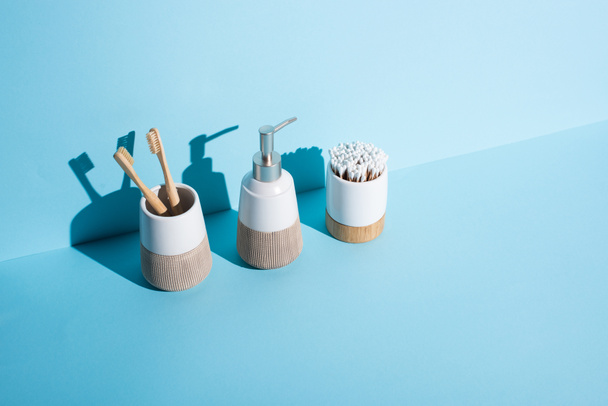 Zahnbürstenhalter mit Ohrstöpseln und Zahnbürsten mit Spender Flüssigseife auf blauem Hintergrund, Zero-Waste-Konzept - Foto, Bild