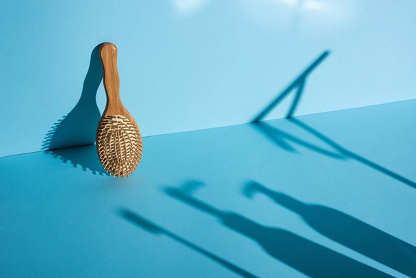 Hair brush and shadows on blue background, zero waste concept - Foto, imagen